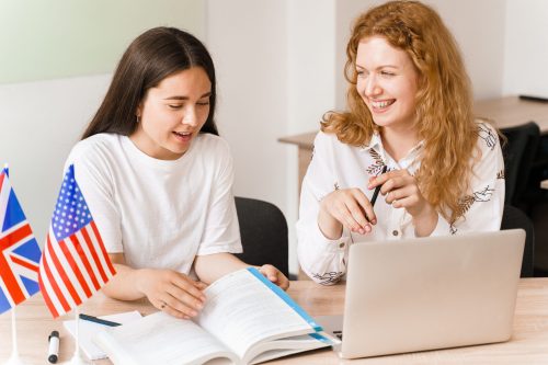 Foreign school private study, smile, laught with a school girl. Teacher explain grammar of native language using laptop. Prepearing to exam with tutor.